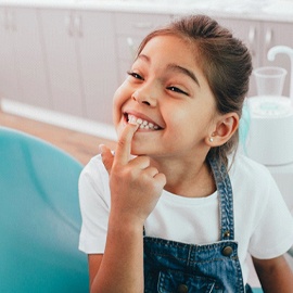 Girl pointing at her teeth visiting Midland children’s emergency dentist