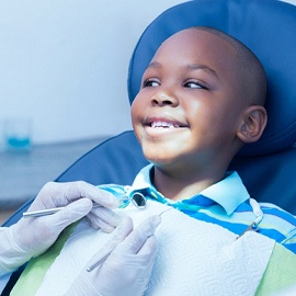 A young boy smiles after a dentist applies dental sealants to his back teeth
