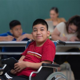 pre-teen in a wheelchair at school holding a smart tablet