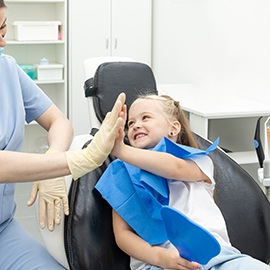 Little girl giving high-five to dental team member