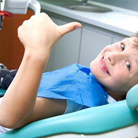 Little boy in dental treatment chair, making thumbs up gesture