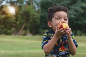 a child snacking on a peach outside
