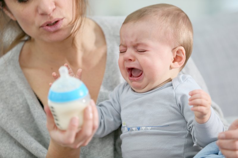 a baby crying while mother holds a bottle